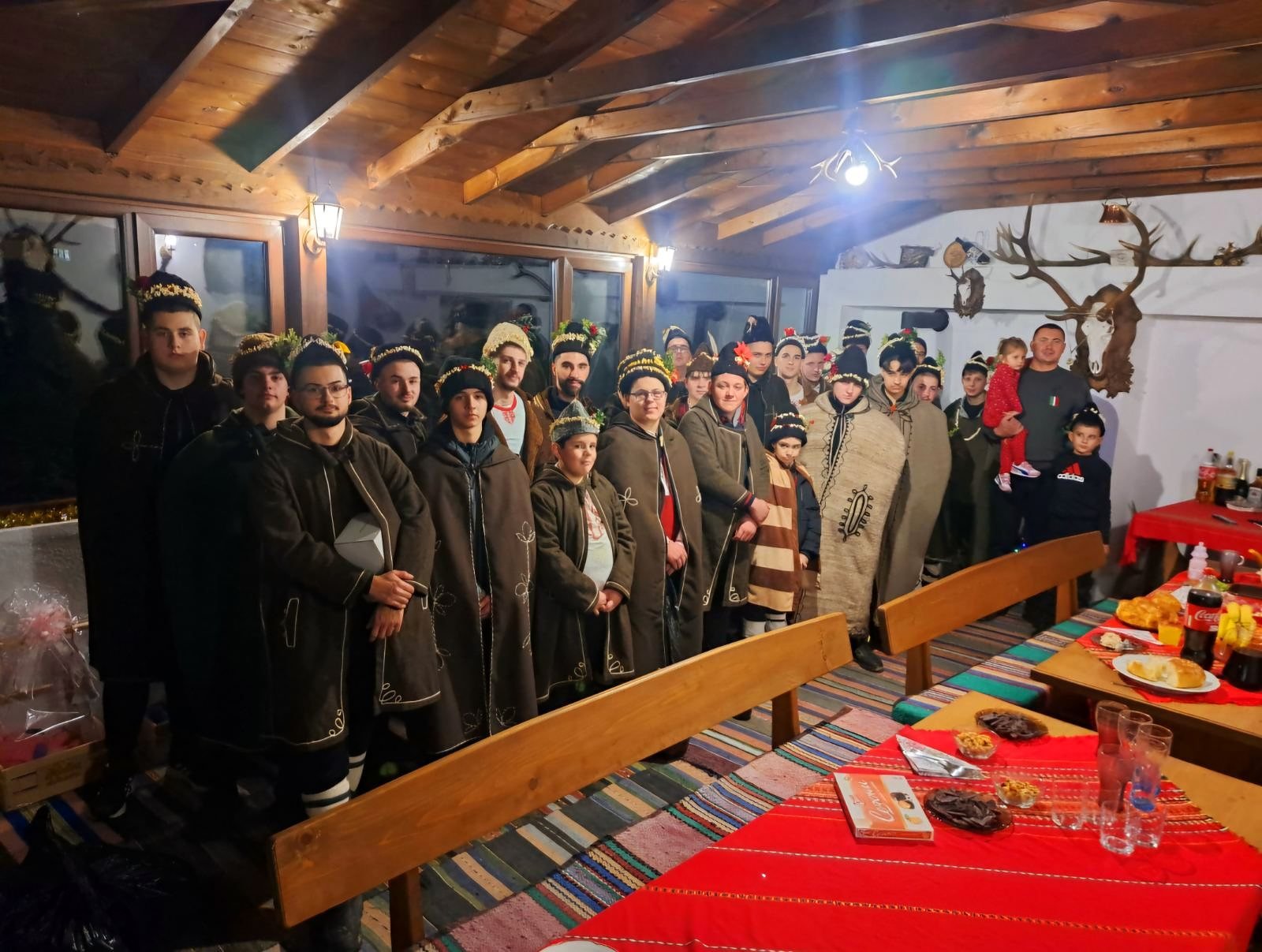 Коледари с калпаци и китки на зимна вечер